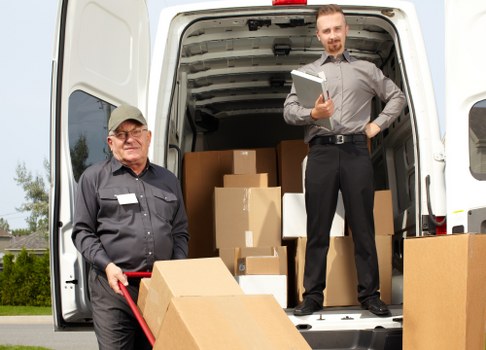 Professional movers handling a piano removal in Belgium with protective equipment